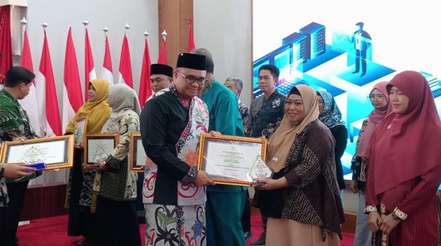 Kepala SMP Negeri 3 Tenggarong saat menerima penghargaan dari Bupati Kukar dr Aulia Rahman Basri. (Lingkarkaltim/M. As'ari)