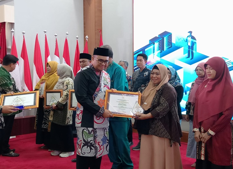 Kepala SMP Negeri 3 Tenggarong saat menerima penghargaan dari Bupati Kukar dr Aulia Rahman Basri. (Lingkarkaltim/M. As'ari)