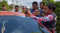 Anggota Damkar mencoba membuka paksa pintu mobil memakai besi pengait, Jumat (19/6/26). (Doc. Disdamkarmatan Kukar)