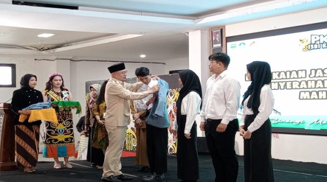 Pemasangan almamater secara simbolis ke perwakilan mahasiswa baru ISBI Kaltim oleh Kepala Disdikbud Kukar Heriansyah. (M. As'ari/Lingkar Kaltim)