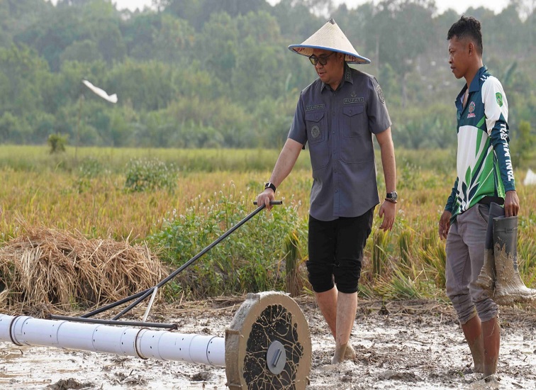 Bupati Kukar dr. Aulia Rahman Basri saat mencoba teknologi pertanian yang dikembangkan oleh petani Desa Manunggal Jaya Kecamatan Tenggarong Seberang. (foto:Achmad)