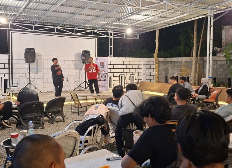 Salah seorang komika dari Komunitas Stand Up Comedy Tenggarong membawakan materi humor di hadapan para penonton saat sesi open mic mingguan di Cafe Haha,Tenggarong, Rabu (7/10/2026) malam. (Dilla/lingkarkaltim)